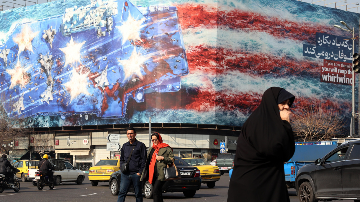 Иранци минават покрай огромен антиамерикански билборд, окачен в Техеран, 27 януари 2026 г.