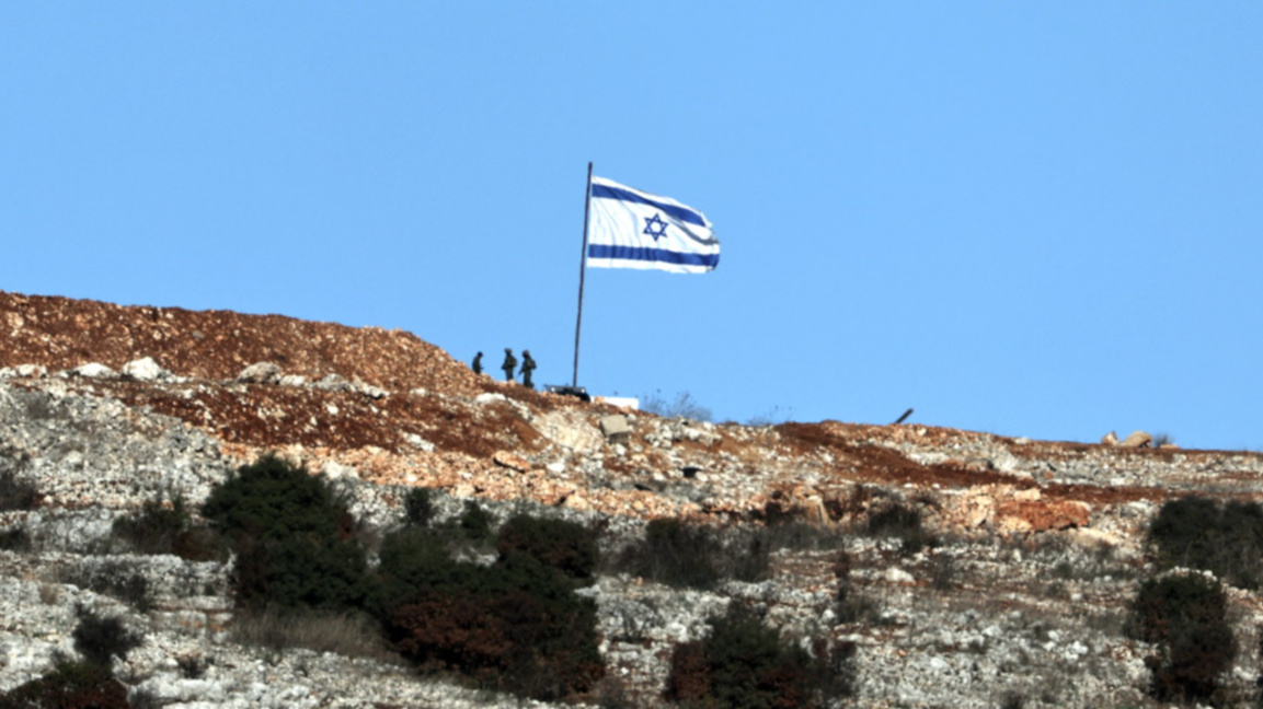 Израелски войници стоят до израелско знаме от ливанската страна на границата, близо до южното ливанско село Марун ал-Рас, 26 ноември 2024 г., на фона на трансгранични военни действия между "Хизбула" и Израел.