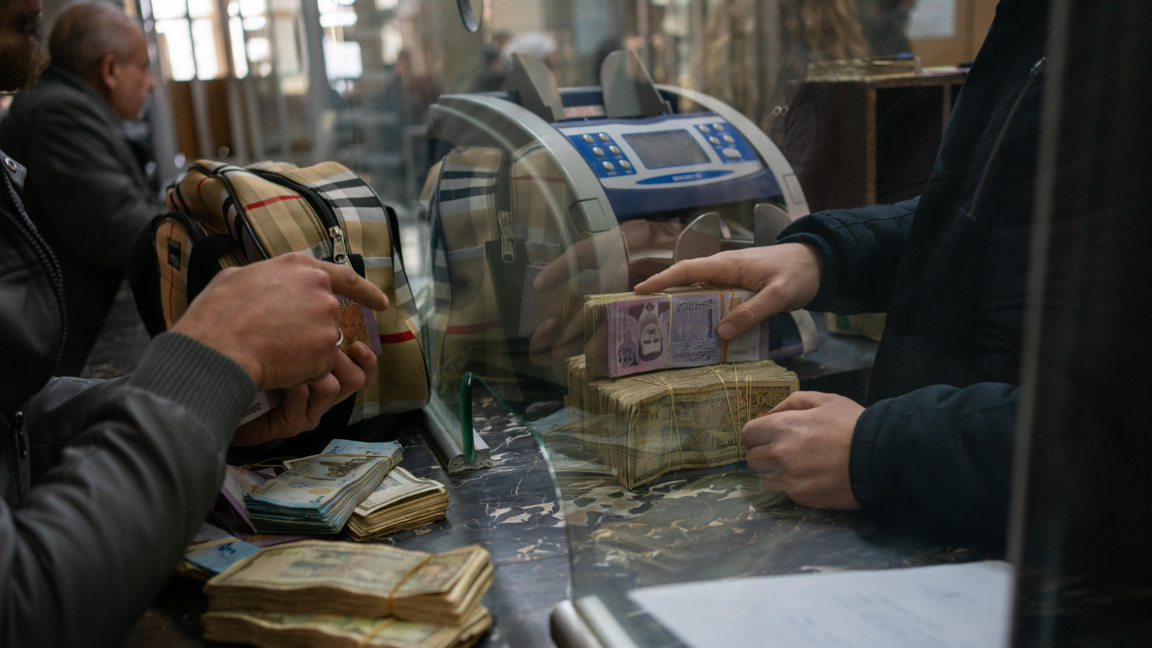 Сирийци броят пари на гише в клон на централната банка в Дамаск