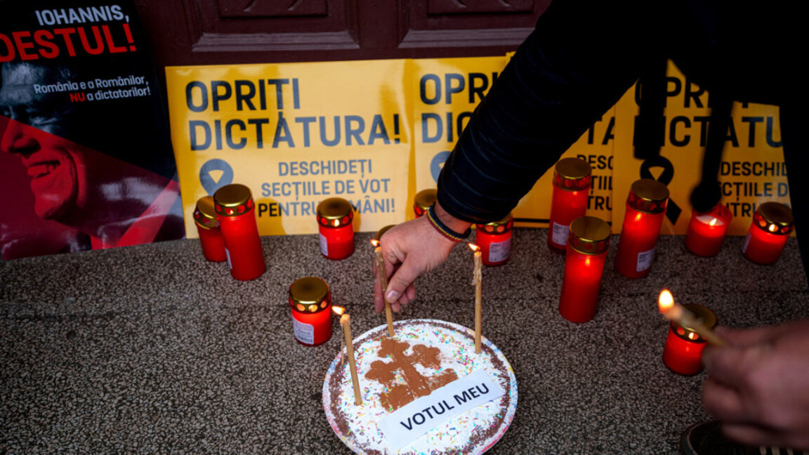Привърженик на Алианса за обединение на румънците пали свещи по време на бдение, организирано пред затворена избирателна секция в Букурещ, 8 декември 2024 г.