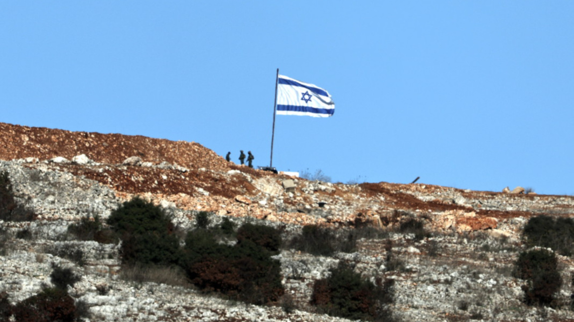 Израелски войници стоят до израелско знаме от ливанската страна на границата, близо до южното ливанско село Марун ал-Рас, 26 ноември 2024 г., на фона на трансгранични военни действия между "Хизбула" и Израел.