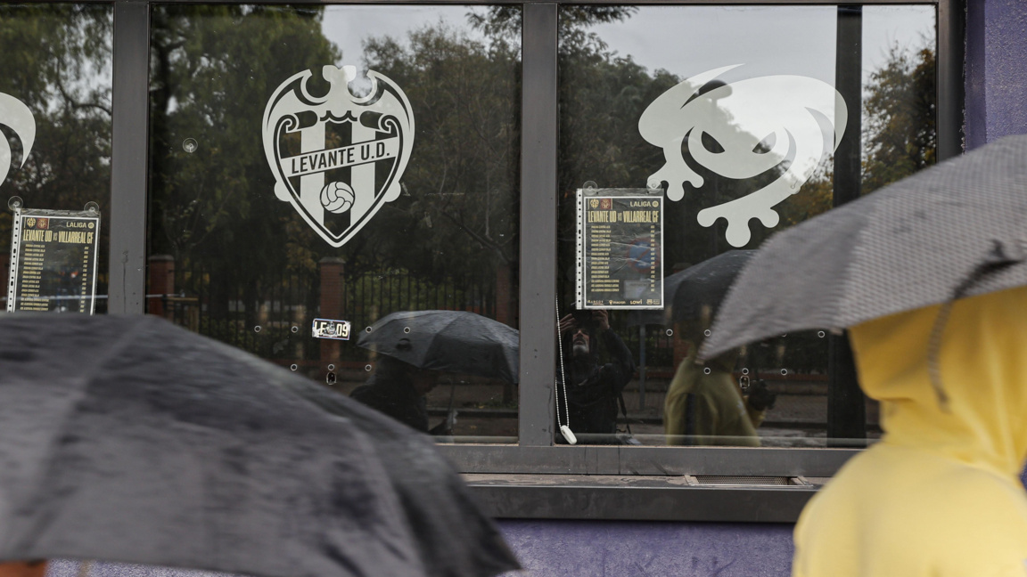 Хора с чадъри минават край затворената билетна каса на стадион "Леванте" във Валенсия, Испания, 14 декември 2025 г.