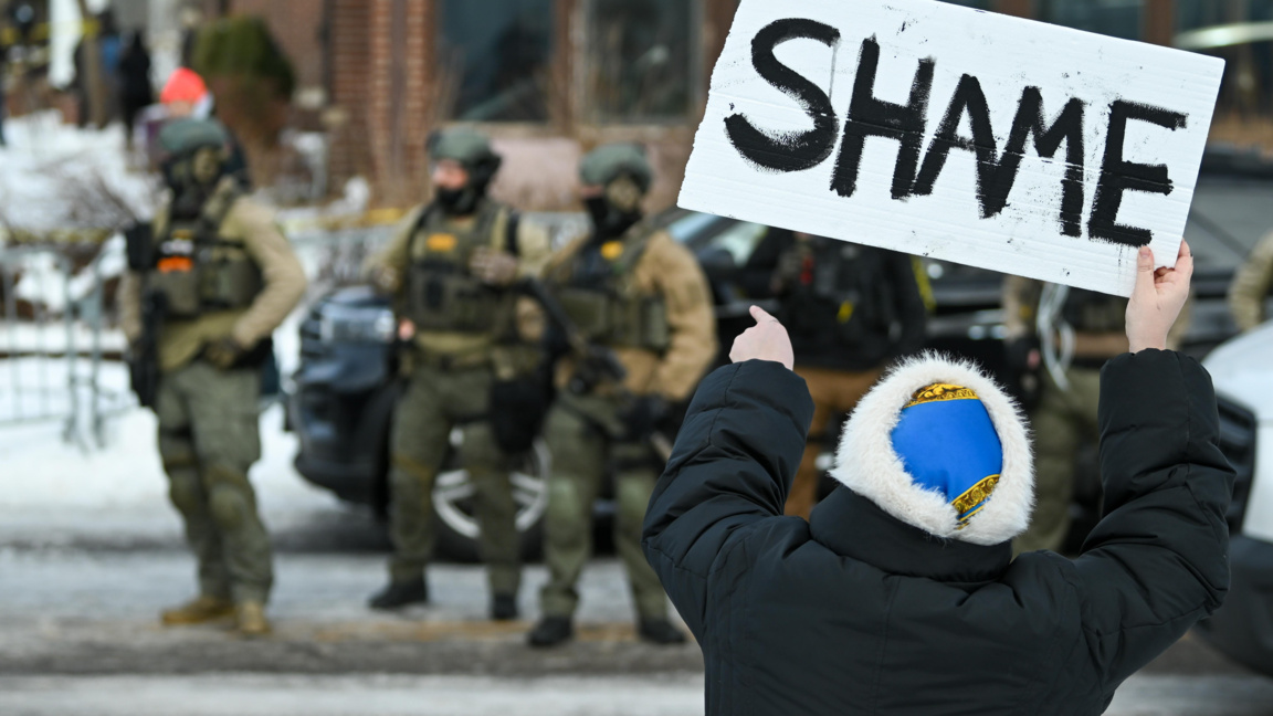 Жена издига плакат с надпис "Срам" на мястото на инцидента в Минеаполис