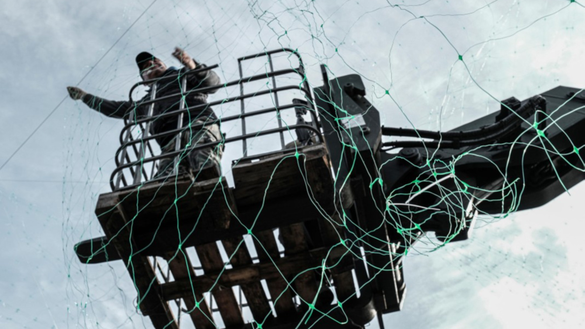 Украински военен разпъва мрежа за защита от дронове.