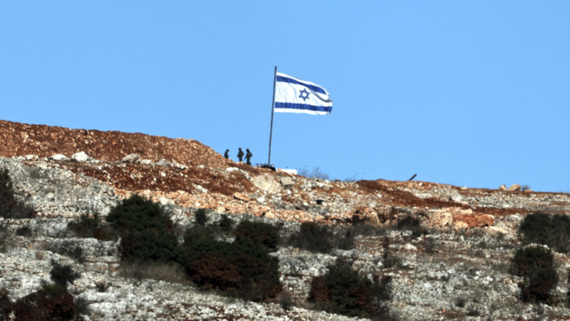 Израелски войници стоят до израелско знаме от ливанската страна на границата, близо до южното ливанско село Марун ал-Рас, 26 ноември 2024 г., на фона на трансгранични военни действия между "Хизбула" и Израел.